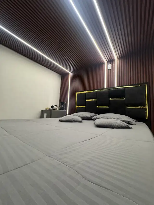 La cama king bajo el techo de listones con luz cálida.