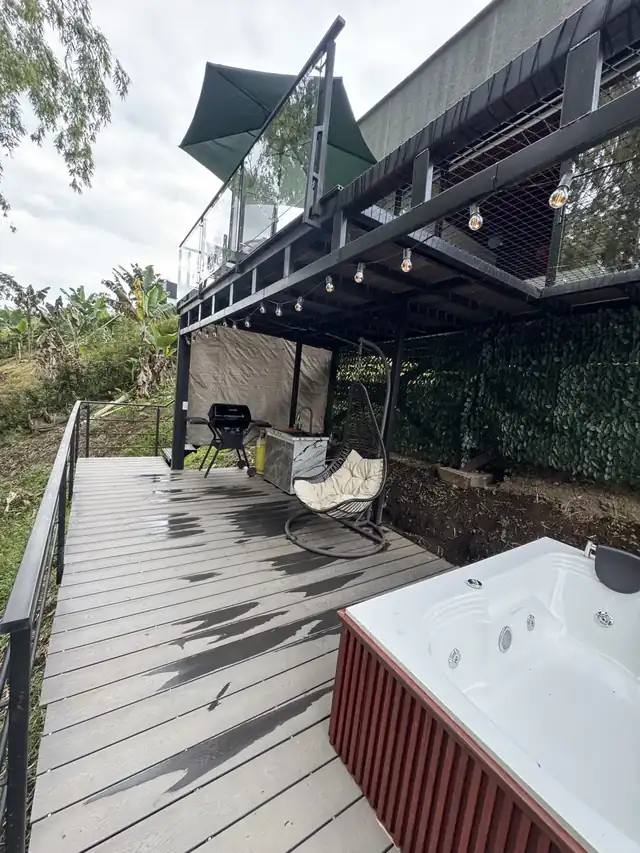 El deck de día con asador, silla colgante y el jacuzzi.