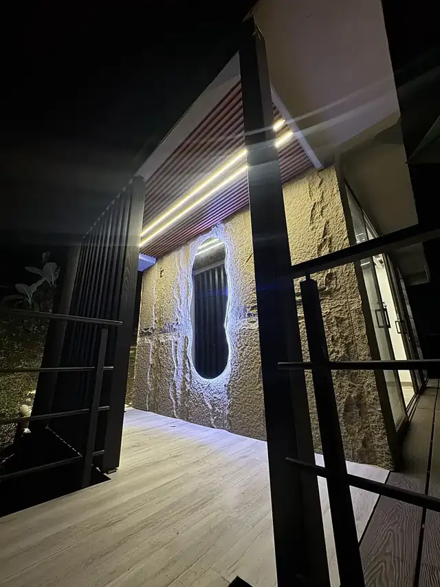La entrada de noche, con ventana ovalada iluminada.