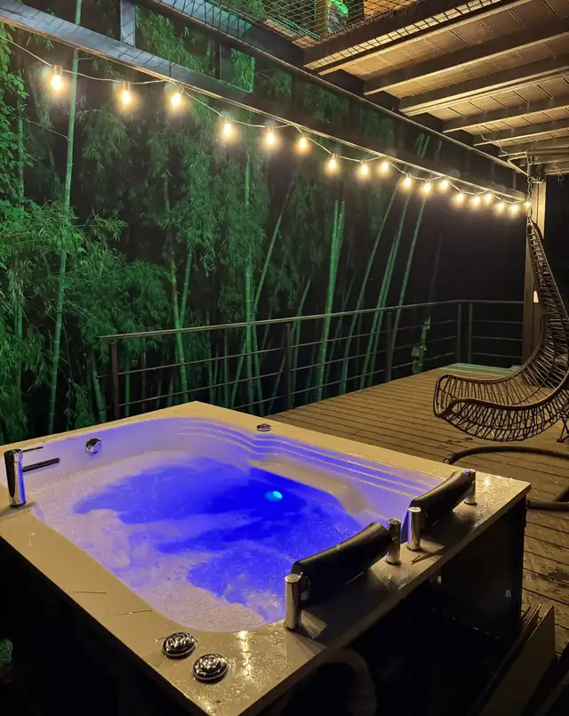 El jacuzzi privado con luz azul, el guadual detrás y una silla colgante al lado.